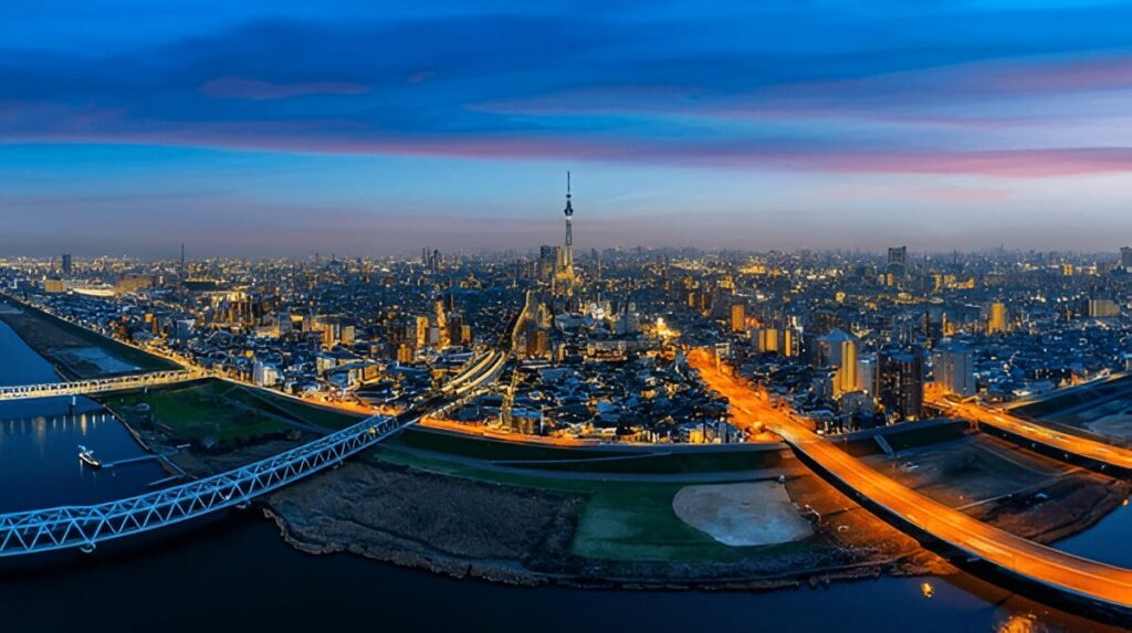 Navigationpaths.com | Kyoto Travel Secrets: Hidden Temples, Sacred Rituals & Undying Charm Aerial view of Tokyo at dusk, with Tokyo Skytree illuminated in the center, city lights glowing, highways crossing over the river, and a vibrant blue and pink sky above.